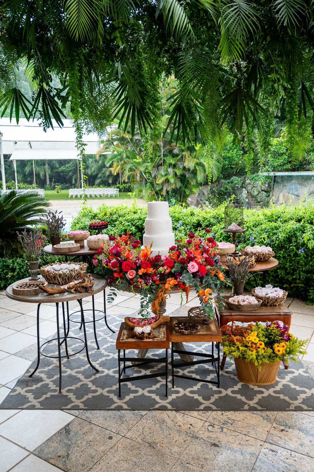 Mesa de doces no jardim com sebe verde ao fundo